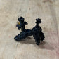 A small black decorative figurine or ornament with a glossy finish, placed on a light beige wooden surface.