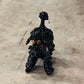 A small glossy black figurine of a dog with yellow eyes, standing on a scratched light brown wooden surface.