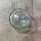 A small, round, clear glass jar or bowl viewed from directly above on a rustic wooden surface.