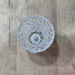 A clear cut-crystal or glass tumbler viewed from above, resting on a rustic wooden surface.