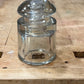 A clear glass insulator bulb, likely a vintage electrical or laboratory glass piece, lying on a rustic wooden workbench.