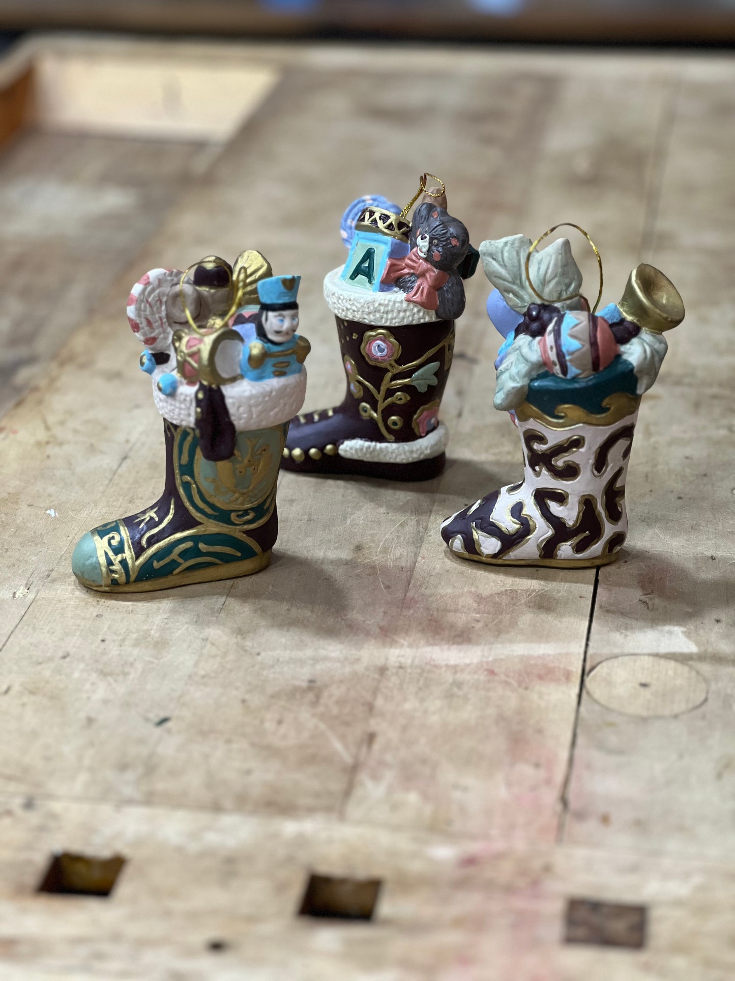 Three small Christmas ornament stockings filled with holiday decorations, displayed on a rustic wooden surface.