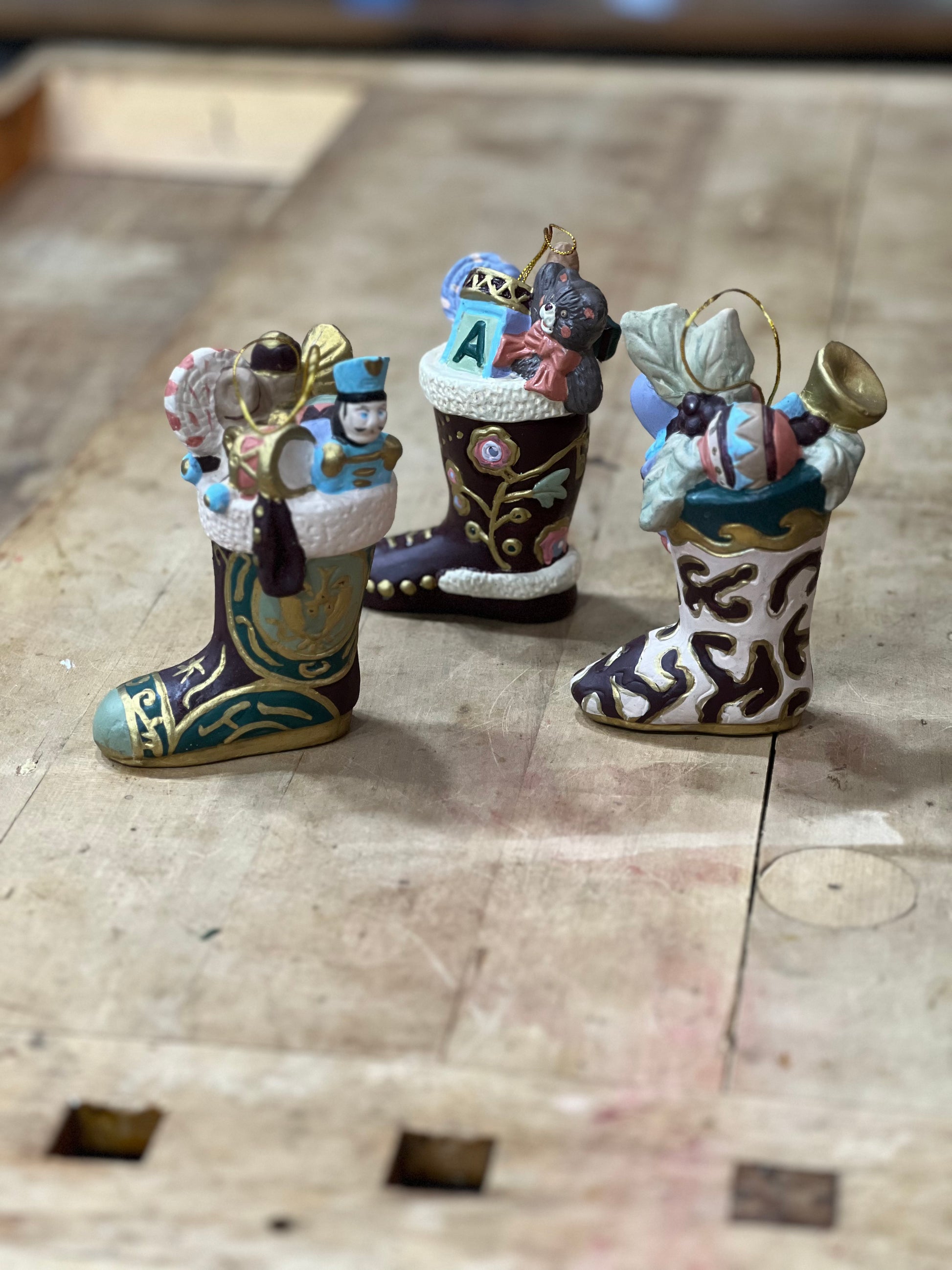 Three small Christmas ornament stockings filled with holiday decorations, displayed on a rustic wooden surface.