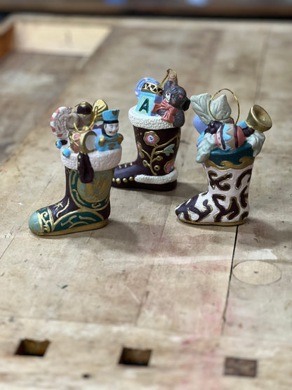 Three small Christmas ornament stockings filled with holiday decorations, displayed on a rustic wooden surface.