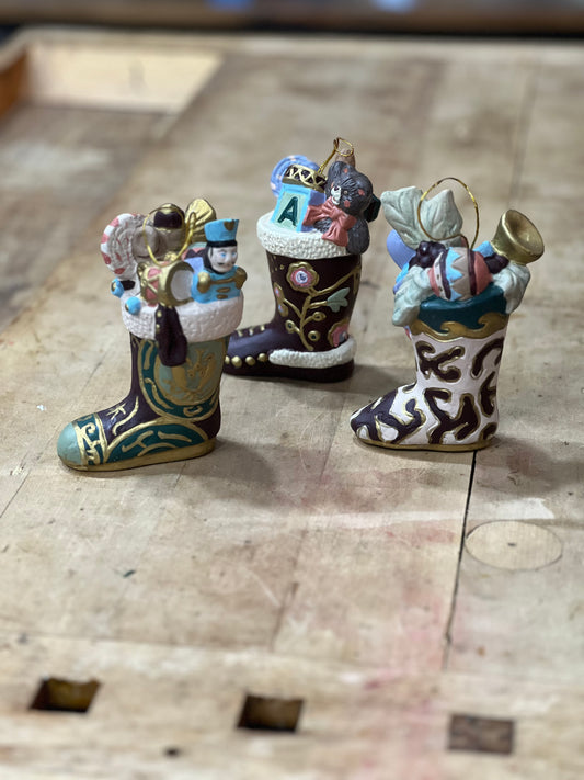 Three small Christmas ornament stockings filled with holiday decorations, displayed on a rustic wooden surface.