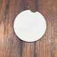 A round off-white ceramic coaster with a small notch on the top edge, placed on a dark brown wooden surface.