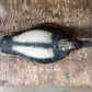 A vintage black and white painted wooden duck deco resting on a rustic, weathered brown wooden surface.