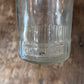 A close-up of a clear glass jar or bottle base embossed with '4 1/2 QUART' on a rustic wooden surface.
