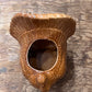 A ceramic acorn-shaped planter with a glossy brown glaze, featuring a textured beak opening and a small protruding acorn detail, shown on a rustic wooden surface.
