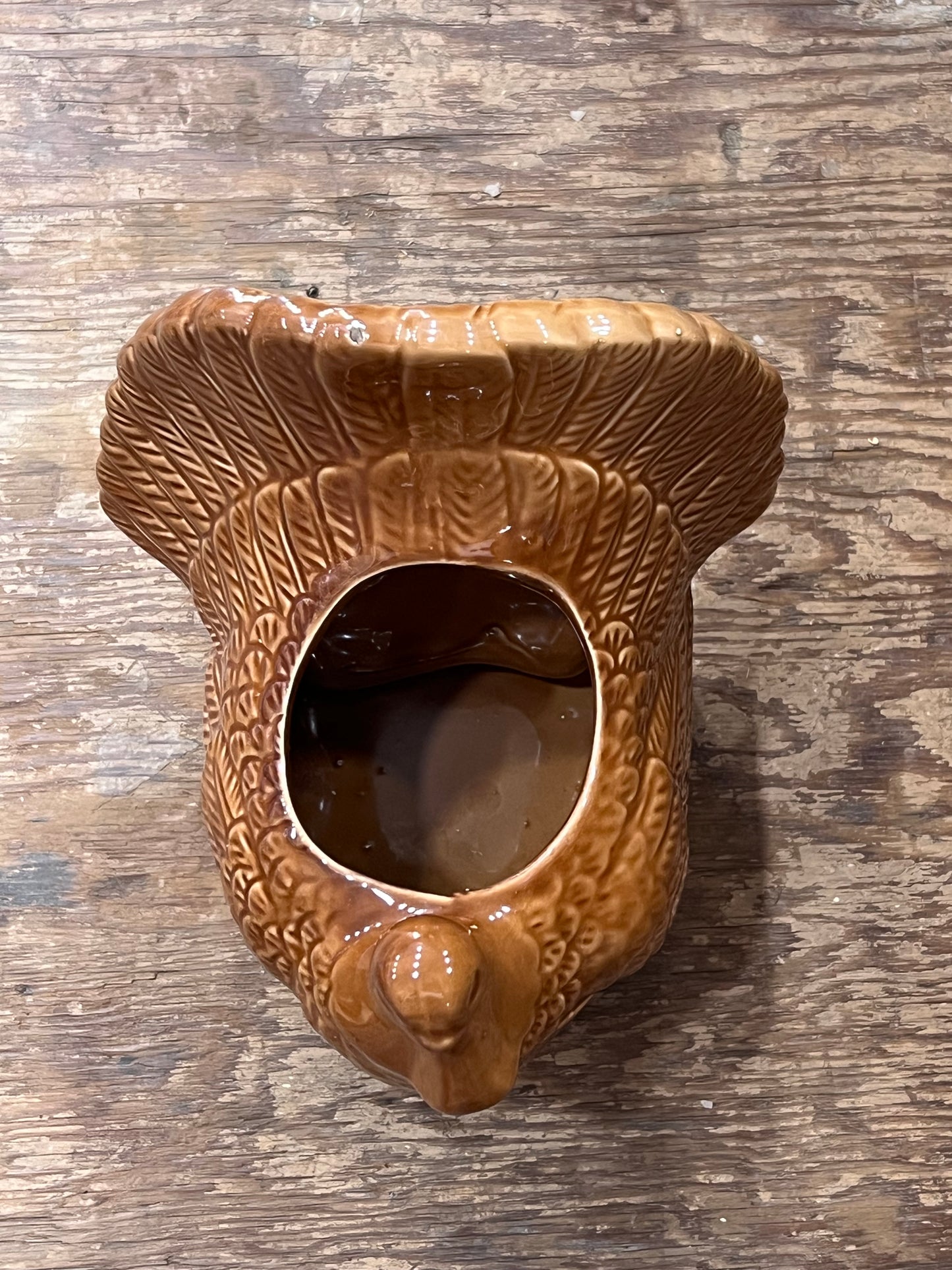A ceramic acorn-shaped planter with a glossy brown glaze, featuring a textured beak opening and a small protruding acorn detail, shown on a rustic wooden surface.
