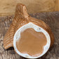 A handmade ceramic planter shaped like a bird, featuring a textured brown exterior and a glossy terracotta-colored interior, displayed on a rustic wooden surface.