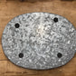 An oval galvanized metal stand or base with four circular feet, photographed from above on a rustic wooden surface.