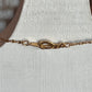Close-up of a gold chain necklace with a lobster clasp, displayed on a textured white jewelry bust.