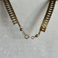 A textured gold-tone chain link necklace displayed on a white mannequin bust, featuring a lobster clasp closure.