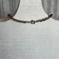 A dark bronze twisted chain link bracelet with a spring ring clasp, displayed on a white painted wooden jewelry bust.