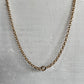 A gold chain necklace with a small ring clasp, displayed on a white textured bust form.