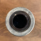 A round, rustic ceramic pot or planter with a textured gray and white glaze, photographed from directly above on a brown wooden surface.