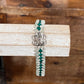 A beaded bracelet with silver-toned beads, dark green faceted beads, and a silver-toned floral clasp, displayed on a light wood block over a rustic wooden background.