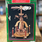Christmas ornament packaging for a 'Choir of Angels Wind Mill' by Shirklin's, featuring a green box with a photo of the wooden wind mill with lit candles.