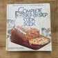 A vintage hardcover cookbook titled 'Complete Step-by-Step Cook Book' by Better Homes and Gardens, featuring a loaf of bread on the cover, placed on a wooden tabletop.