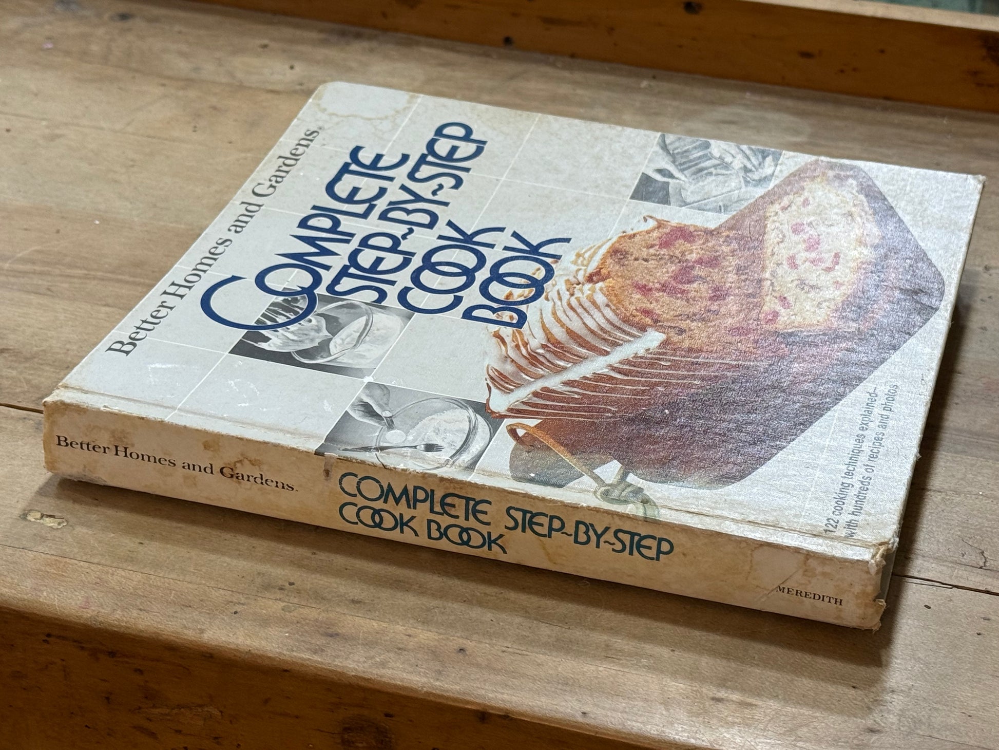 A vintage hardcover cookbook titled 'Complete Step-by-Step Cook Book' by Better Homes and Gardens, resting on a wooden surface.