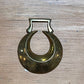 A vintage brass crescent moon ring with a rectangular top, displayed on a light-colored wooden surface.