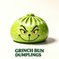 A green Grinch-shaped dumpling with a printed Grinch face, shown on a white background with the text 'GRINCH BUN DUMLINGS' below.